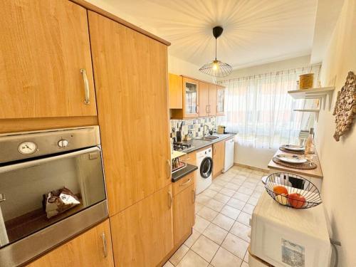 La cuisine est équipée d'armoires en bois et d'un four en acier inoxydable. dans l'établissement Cosy 2 pièces élégant proche gare et port Vauban, à Antibes