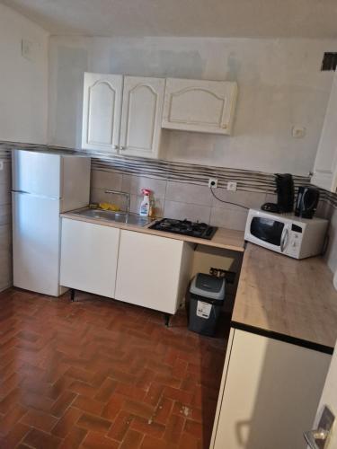 La cuisine est équipée d'un réfrigérateur blanc et d'un four micro-ondes. dans l'établissement Une chambre Salle de bain Wi-Fi, à Bédarrides