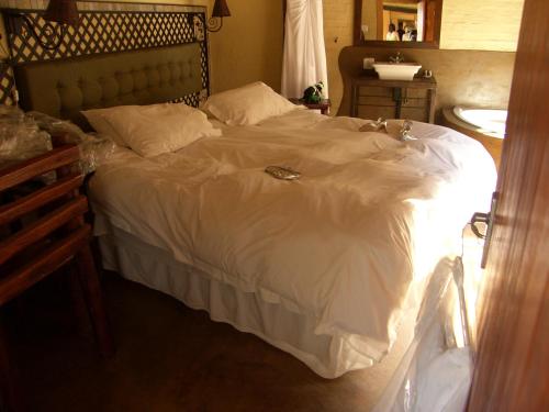 a large bed with white sheets and pillows at African Silhouette Guesthouse in Benoni