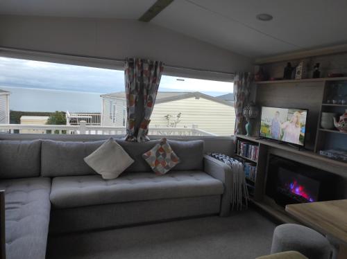 a living room with a couch and a tv at Torbay Holiday Home at The Waterside Holiday Park - With Deck and Sea View in Torquay