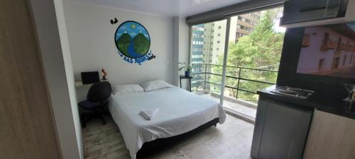 a bedroom with a bed and a balcony with a television at Las Aguas Inner Experience in Bogotá