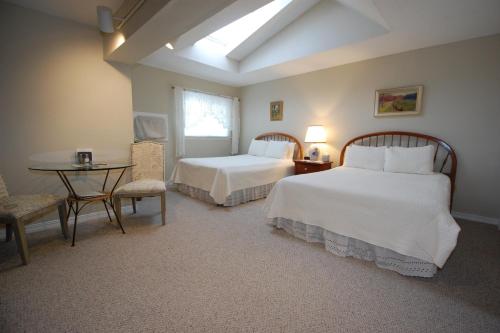 a bedroom with two beds and a table and a window at Shaker Mill Inn in West Stockbridge