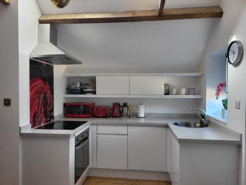 a white kitchen with white cabinets and a sink at Beautiful Self Contained Cottages in Westbury in Westbury