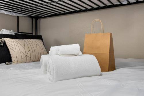 a pile of towels on a bed with a shopping bag at Hines Haven - Unit 2 - Perfect BNB for YOU in Peoria