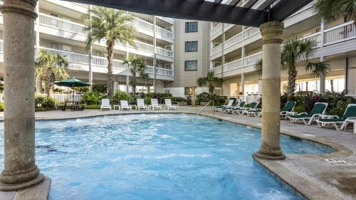 a large swimming pool with chairs and a building at Oceanfront Condo Heated Pool Walk to Beach Views in Galveston