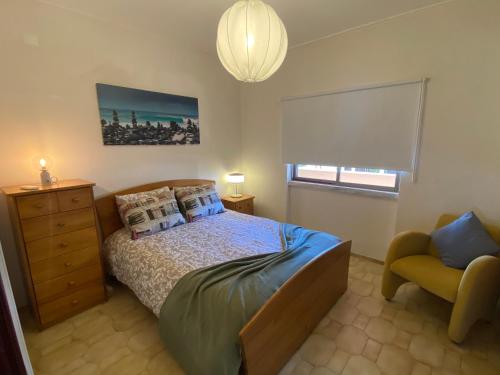 a bedroom with a bed and a chair and a window at Silver Moon Beach House in Lagos