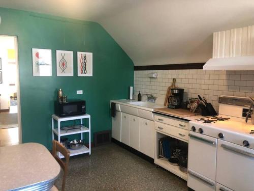 a kitchen with green walls and white cabinets and a stove at Gallery Loft of Oak Park #1 Top Host in IL in Oak Park