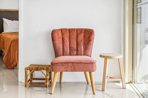 a chair and stool in a room with a bed at Cullen Bay 3BR Oceanview Bliss in Larrakeyah
