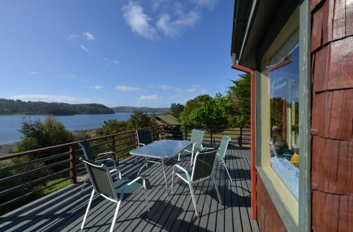 a deck with a table and chairs and a view of the water at Cabañas Alcamar in Castro