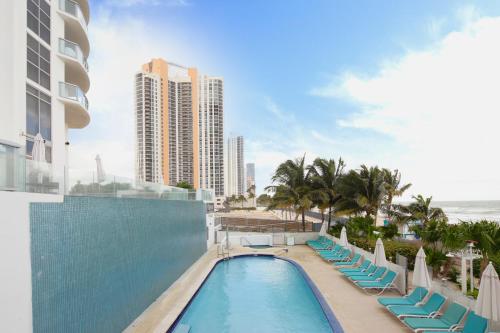 a swimming pool with lounge chairs and the ocean at Marenas Beach Resort Private Luxury Suites in Miami Beach