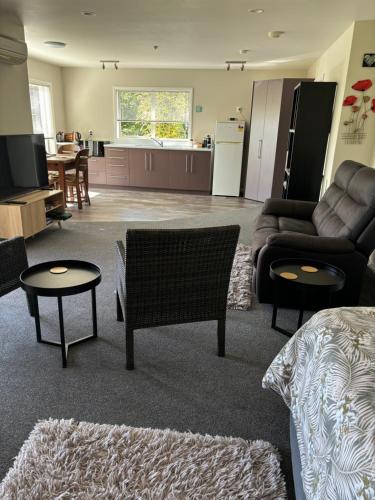 a living room with a couch and chairs and a kitchen at Private Guest Suite in Mapua