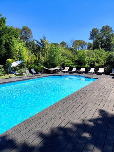 une piscine avec des chaises longues sur une terrasse en bois dans l'établissement Villa Sainte Victoire, à Peynier