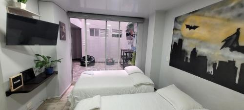 a room with two beds and a tv and a window at Las Aguas Inner Experience in Bogotá