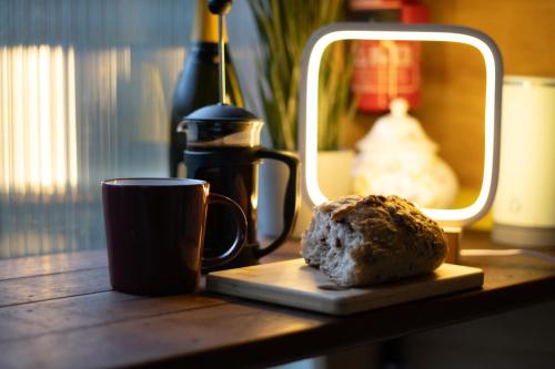 a table with a cup of coffee and a doughnut on it at Architect-Designed Rural Cabin - Year Round Retreat in Market Drayton