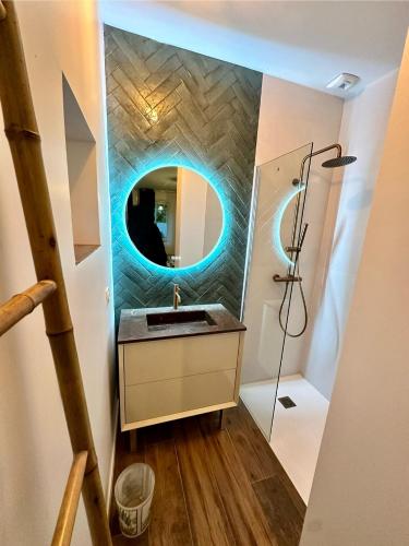 La salle de bains est pourvue d'un lavabo et d'un miroir circulaire. dans l'établissement Gîte de plain-pied, à Les Abrets en Dauphine