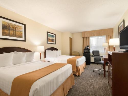 a hotel room with two beds and a flat screen tv at Travelodge by Wyndham Edmonton South in Edmonton