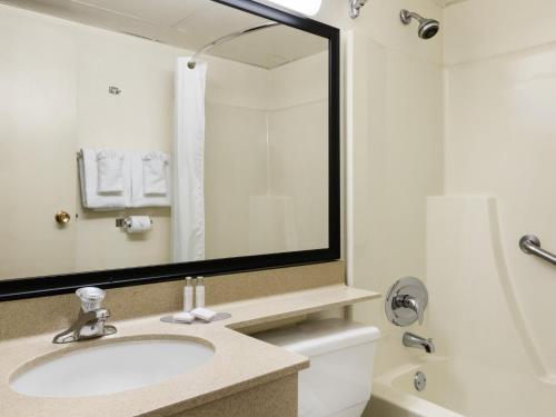 a bathroom with a sink and a mirror at Travelodge by Wyndham Edmonton South in Edmonton