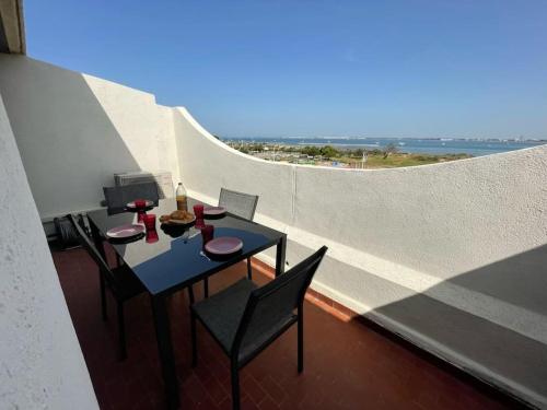une table et des chaises sur un balcon avec vue dans l'établissement Appartement T2 front de mer, vue panoramique, au Grau-du-Roi