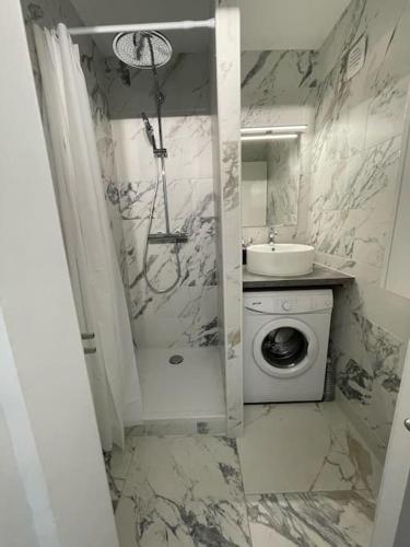 une salle de bain avec un lavabo et une machine à laver dans l'établissement Appartement T2 front de mer, vue panoramique, au Grau-du-Roi