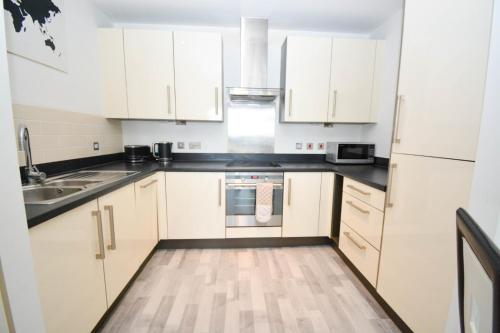 a kitchen with white cabinets and a sink at GioGio - Comfortable Stratford Flat with Stunning Views in London