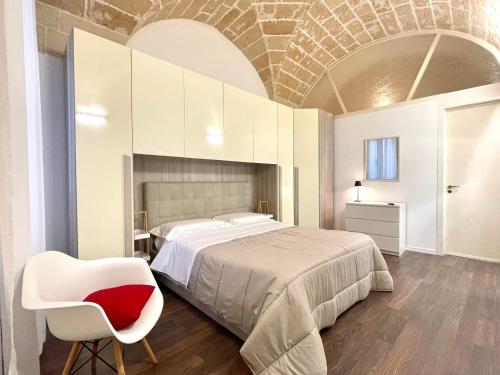 a bedroom with a large bed and a chair at Santa Croce - vivi il cuore della città in Lecce