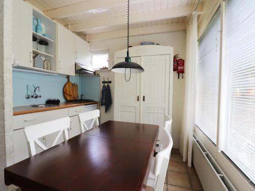 a kitchen with a wooden table and white cabinets at Forest House in Appelscha near National Parks in Appelscha