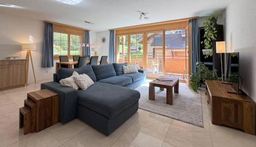 a living room with a blue couch and a tv at Family Frame Apartment in Lauterbrunnen