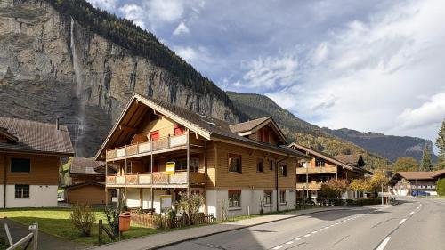 a building on the side of a road next to a mountain at Family Frame Apartment in Lauterbrunnen