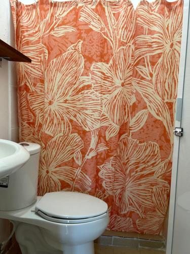 a bathroom with a toilet and a flower shower curtain at Casa Nayeeche, Hospedaje & Dive Center in Mazunte