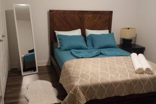 a bedroom with a bed with blue pillows and a mirror at Logement neuf, spacieux in Longueuil
