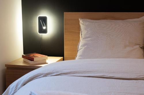 un lit avec une table de nuit, un livre et une lampe dans l'établissement Le Confort de l'Ours, à Mulhouse