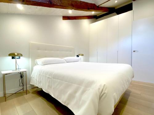 a white bedroom with a large white bed and a lamp at San Juan Centro Histórico in Burgos