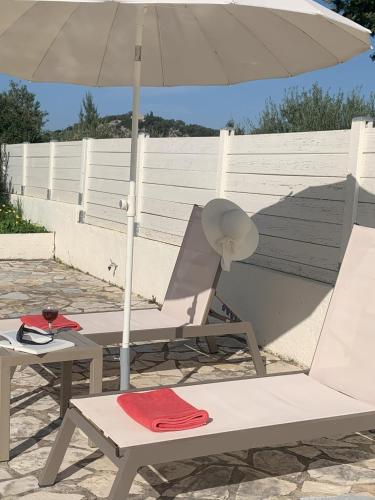 an umbrella and two chairs and a table with a hat at Villa Fedrita in Acharavi