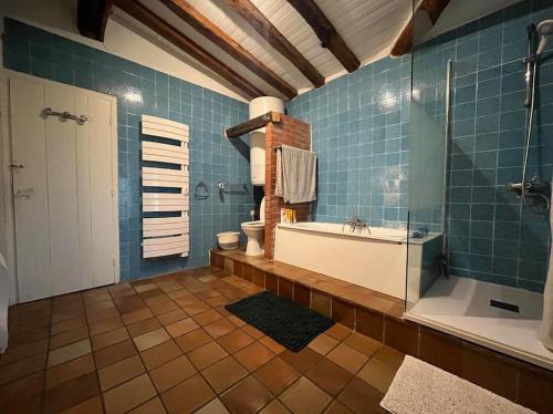 La salle de bains est pourvue d'une baignoire et d'une douche avec du carrelage bleu. dans l'établissement Landaise 12 couchages - piscine tennis boulodrome privés - proche lacs & océan, à Ychoux