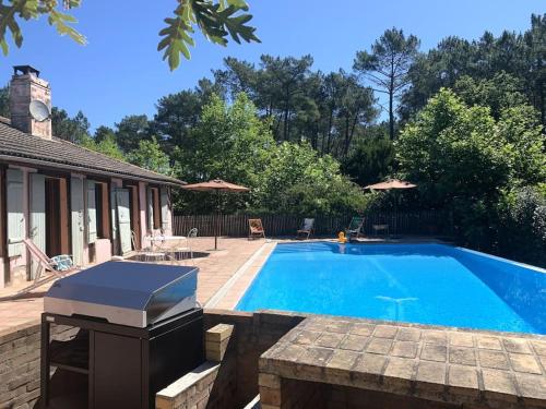 une piscine dans une cour avec un patio dans l'établissement Landaise 12 couchages - piscine tennis boulodrome privés - proche lacs & océan, à Ychoux