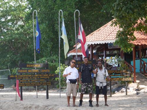 a group of three men standing in front of flags at Cabinas Tito in Cahuita