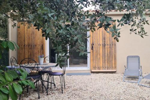 un patio avec une table et des chaises sous un arbre dans l'établissement Studio en vaucluse , campagne jacuzzi près d Orange, à Mondragon