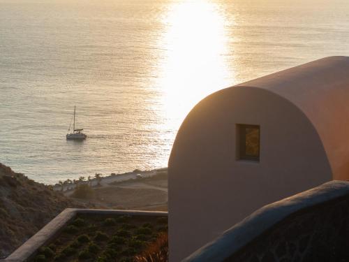 a boat in the water next to a beach at Bay View Residences Santorini in Akrotiri