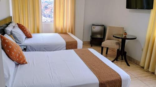 a hotel room with two beds and a table at Riosol Hotel Tarapoto in Tarapoto