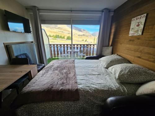 une chambre avec un grand lit avec une grande fenêtre dans l'établissement Appart ski aux pieds Alpe d'Huez, à Huez