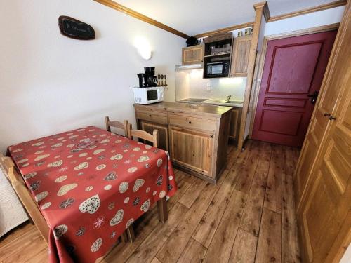 une petite cuisine avec une table et une porte rouge dans l'établissement Résidence Le Clos Vanoise - 2 Pièces pour 6 Personnes MAE-4501, à Bessans