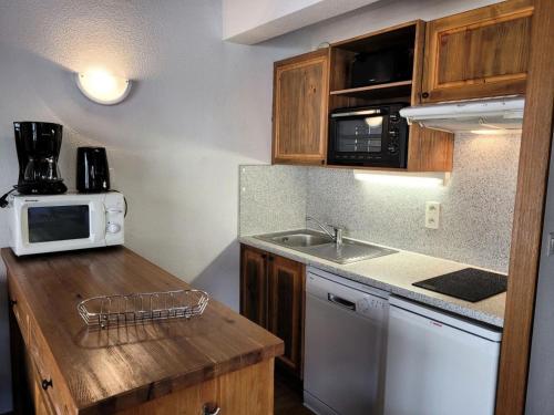 une petite cuisine avec un évier et un micro-ondes dans l'établissement Résidence Le Clos Vanoise - Studi mezzanine chaleureux MAE-4561, à Bessans