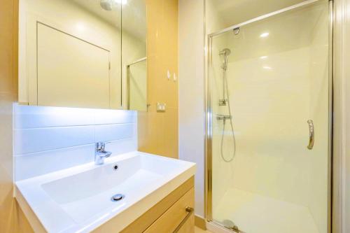 a bathroom with a white sink and a shower at Spectacular Auckland CBD Views in Auckland