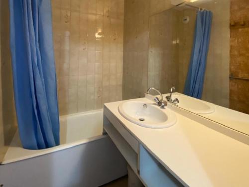 La salle de bains est pourvue d'un lavabo et d'un rideau de douche bleu. dans l'établissement Résidence Parrachee - 2 Pièces pour 5 Personnes MAE-4631, à Val Cenis