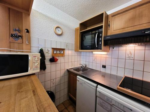 une petite cuisine avec un micro-ondes et un évier dans l'établissement Résidence Albaron - Studio pour 4 Personnes MAE-4711, à Bessans