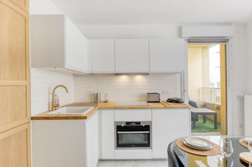 une cuisine blanche avec un évier et une cuisinière dans l'établissement Appartement Moderne T2 Proche PARIS Parking, à Bondy