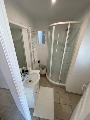 une salle de bain blanche avec une douche et un lavabo dans l'établissement Le Village - cosy flat 5 min walk away from sea, à Nice