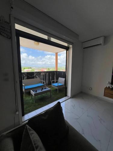a living room with a large window and a couch at Appartement confortable à Ducos, 55 m² avec terrasse in Ducos