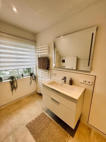 a bathroom with a sink and a mirror and a window at Ferienwohnung Amselweg Haiger in Haiger