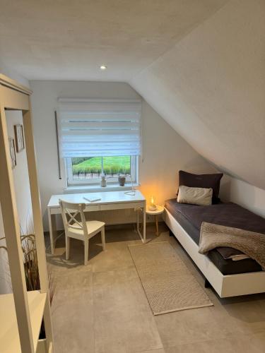 a bedroom with a bed and a desk and a window at Ferienwohnung Amselweg Haiger in Haiger
